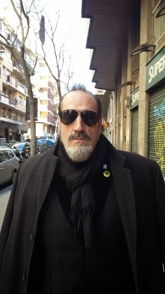 Retrato de un hombre con gafas de sol y abrigo negro en una calle